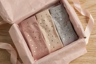 Coffret cadeau chaussettes paillettes femme avec modèles brillants en fils métalliques rose gold, champagne et argent présentés dans une boîte élégante sur bois clair